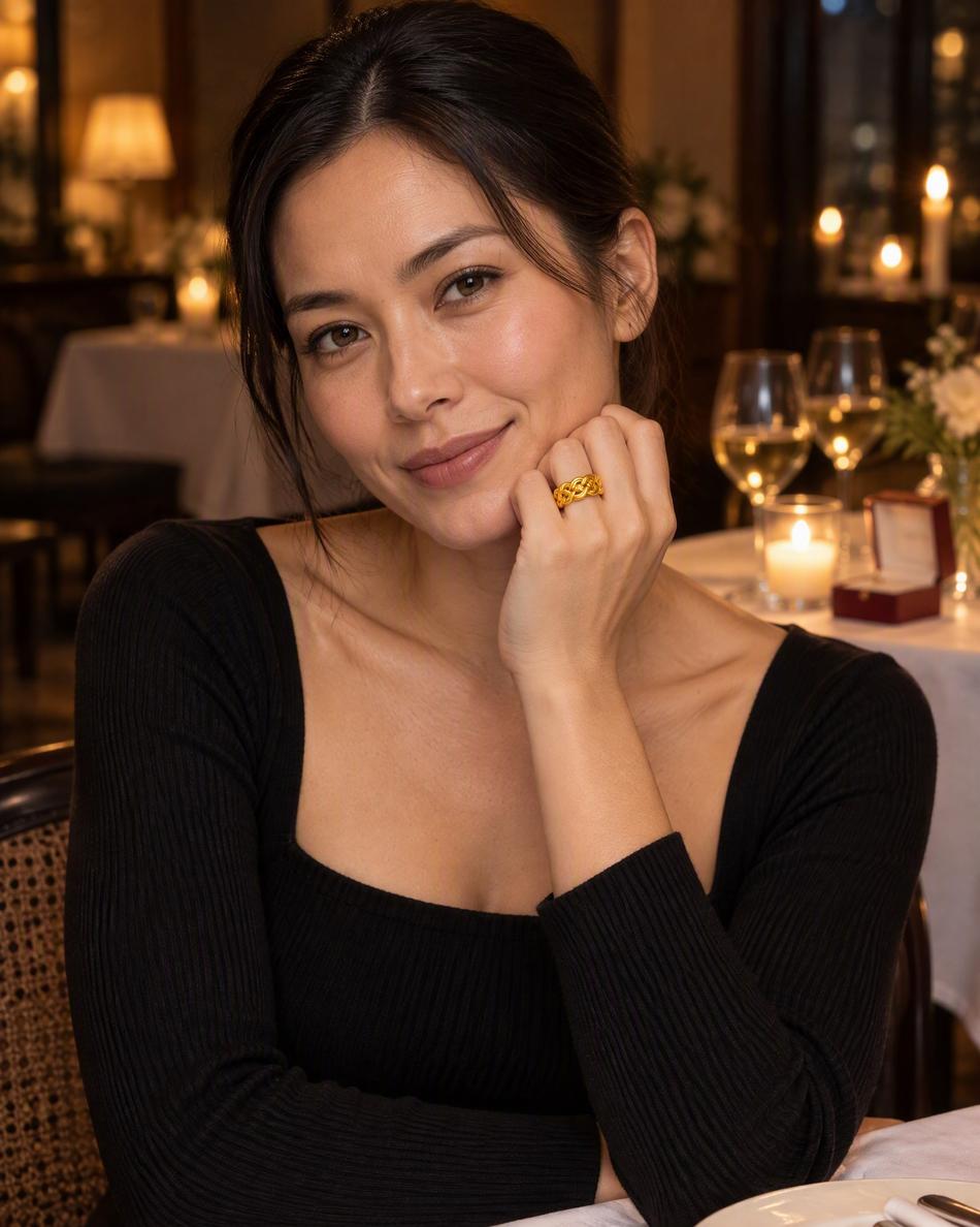 A woman wearing a gold knot ring at a candlelit table for two